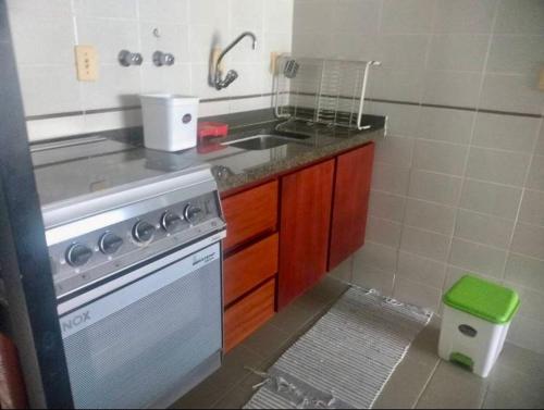 uma pequena cozinha com um lavatório e um fogão em Frente ao Mar Del Plata em São Vicente