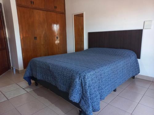 1 dormitorio con 1 cama azul y armario de madera en Departamento Céntrico en Posadas