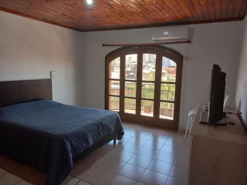 1 dormitorio con 1 cama, TV y ventana en Departamento Céntrico en Posadas