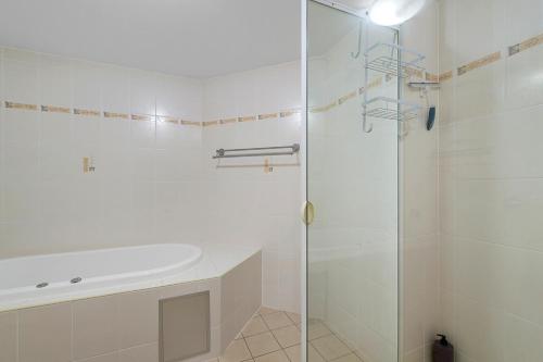 baño blanco con ducha y lavamanos en Flightdeck 203 5-7 Clarence Street PM, en Port Macquarie