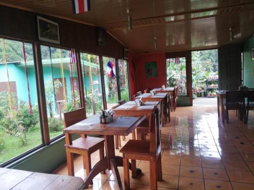 a row of wooden tables in a restaurant with windows at Cabañas San gerardo in San Gerardo de Dota