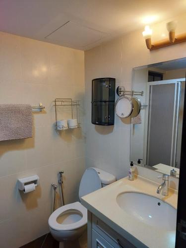 a bathroom with a toilet and a sink and a mirror at Batu Ferringhi Luxury Seaview Suite - 3Br in Batu Ferringhi