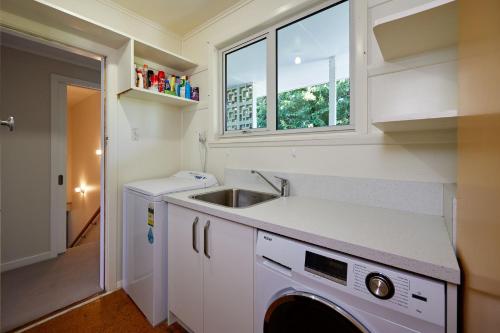 a kitchen with a sink and a washing machine at Views on Scarborough in Kaikoura