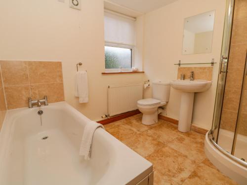 a bathroom with a tub and a toilet and a sink at The Old Chapel in Bishop Wilton