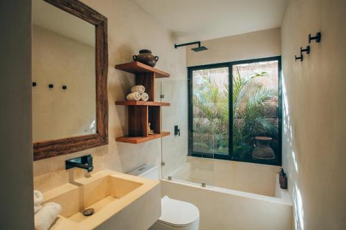 a bathroom with a sink and a toilet and a window at Vida Boho Apart 3 with special fee to access Hotel Bardo in Tulum