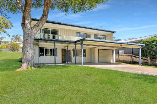a house with a tree in front of it at Lilli Pilli House by Experience Jervis Bay in Vincentia