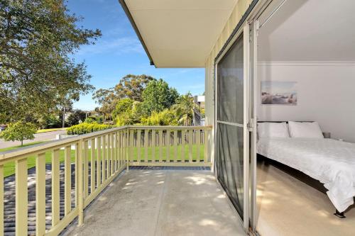 a bedroom with a balcony with a bed and a window at Lilli Pilli House by Experience Jervis Bay in Vincentia