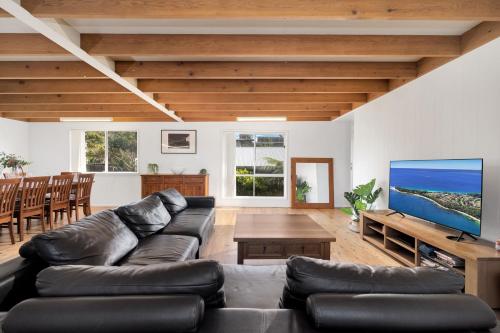 a living room with a couch and a large screen tv at Lilli Pilli House by Experience Jervis Bay in Vincentia