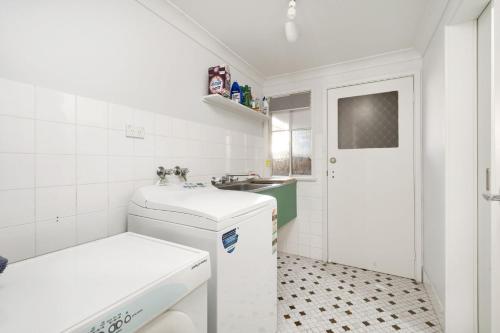 a white bathroom with a sink and a toilet at Lilli Pilli House by Experience Jervis Bay in Vincentia