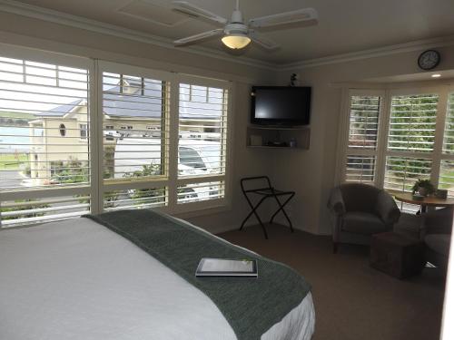 a bedroom with a bed and a tv and windows at On The Terrace Stanley in Stanley