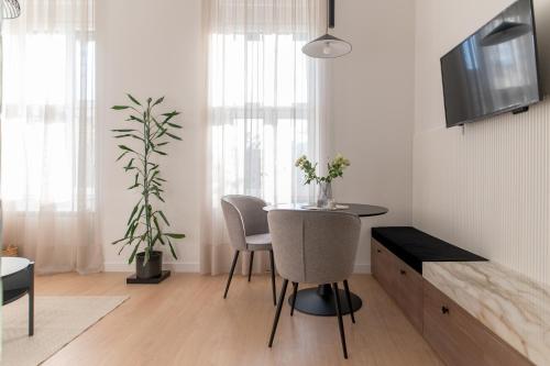 ein Wohnzimmer mit Tisch und Stühlen und einem Fernseher in der Unterkunft Deluxe Dunavska Apartment 3 in Novi Sad