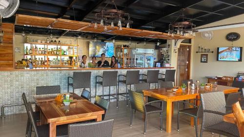 un restaurante con mesas y sillas de madera y un bar en Alona's Coral Garden Resort (Adult-Only), en Panglao