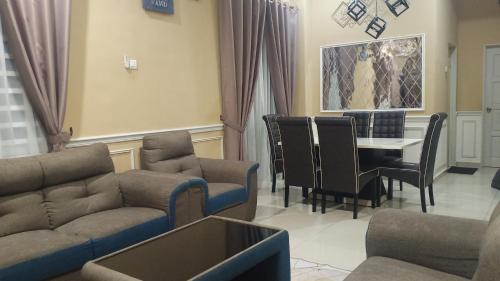ein Wohnzimmer mit einem Sofa, einem Tisch und Stühlen in der Unterkunft illa Bella Homestay Jasin in Jasin