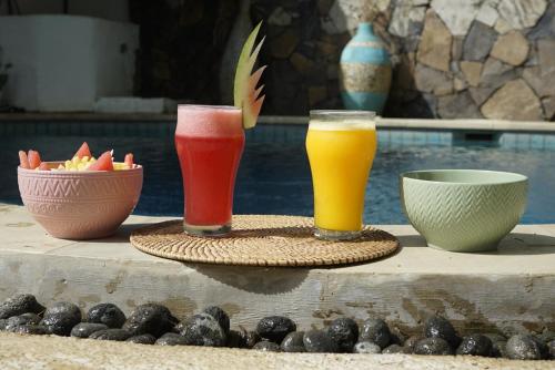 three drinks sitting on a table next to a pool at Gili Breeze Tropical Bungalows in Gili Trawangan