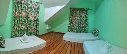 two beds in a room with green walls and wooden floors at Blue Lagoon Inn in Pagudpud