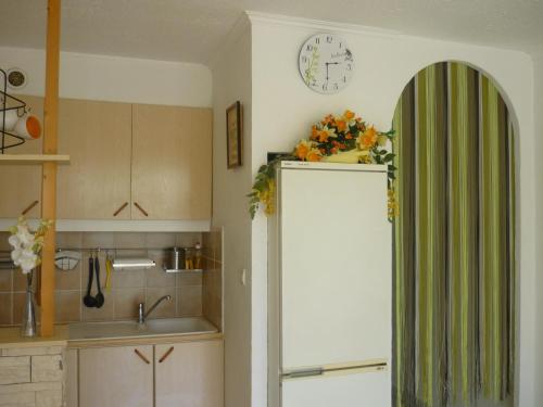 a kitchen with a refrigerator and a clock on the wall at Le Capitole in Narbonne-Plage