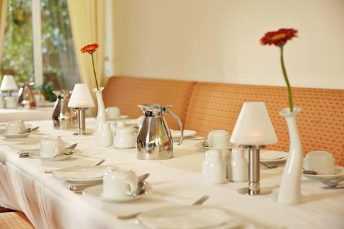 a long table with white dishes and vases with flowers at H+ Hotel Stade Herzog Widukind in Stade