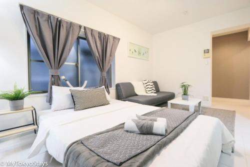 a bedroom with a large white bed and a chair at NEW! Time Square Shibuya Modern Unit. Prime Location in Tokyo