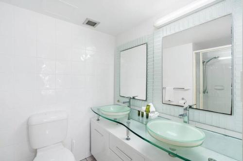 a bathroom with two sinks and a toilet and a mirror at Solnamara - Hosted by Burleigh Letting in Gold Coast