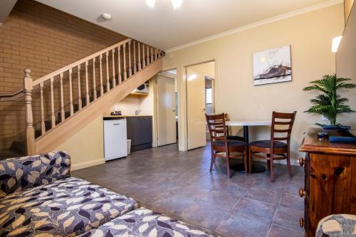 un soggiorno con tavolo, sedie e scala di Albury Georgian Motel & Suites ad Albury