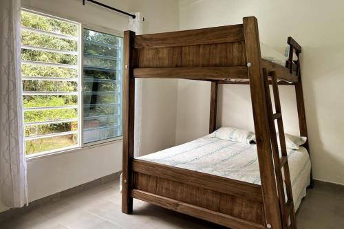 Litera de madera en habitación con ventana en Casa campestre con piscina y jacuzzi cerca a Ginebra Valle del Cauca en Guacarí