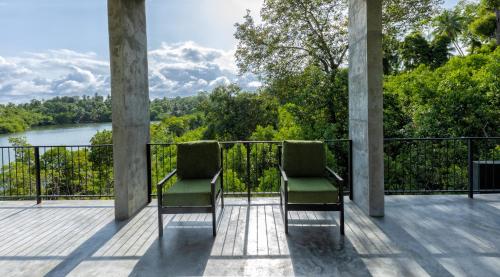 two chairs sitting on a deck with a view of a river at Splendour Residence in Balapitiya