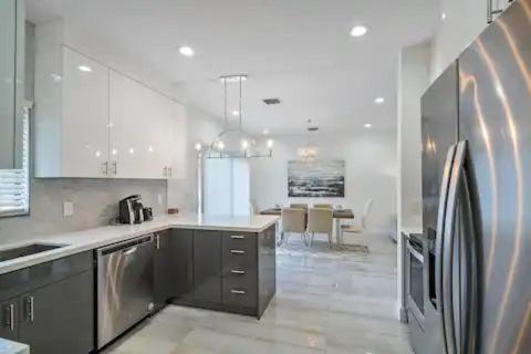a kitchen with a stainless steel refrigerator and a table at New Townhome near Wilton/Las Olas/Beach in Fort Lauderdale