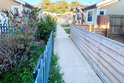 a fence in front of a yard with flowers at LBC Paradise Bungalow in Long Beach