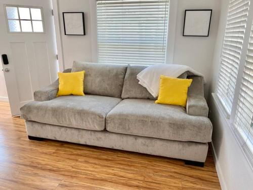 a couch with two yellow pillows in a living room at LBC Paradise Bungalow in Long Beach