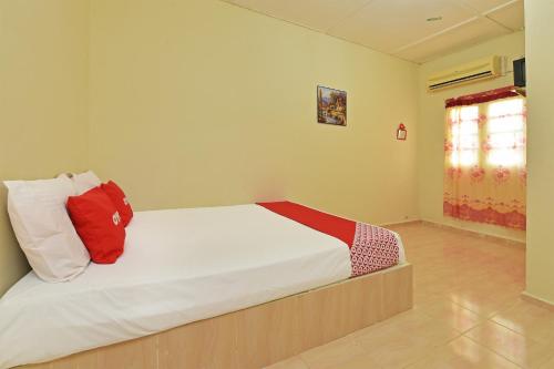 um quarto com uma cama com almofadas vermelhas e brancas em OYO 90689 Chalet Kak Siti em Kuala Terengganu