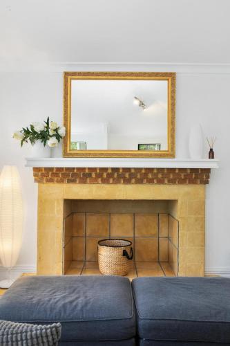 a mirror above a fireplace with a blue couch at Pet Friendly Family Favourite - Kangaroo and Fairway Views with Air Con in Dunsborough