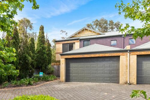a house with two garage doors in a driveway at Pet Friendly Family Favourite - Kangaroo and Fairway Views with Air Con in Dunsborough