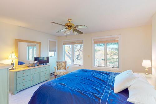 a bedroom with a blue bed and a ceiling fan at SaltBox 1B in White River Junction
