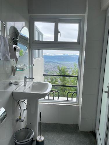 a bathroom with a sink and a large window at Hotel Pokharaeye in Pokhara