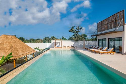 uma piscina com cadeiras e uma casa em The Waves Tulum em Tulum