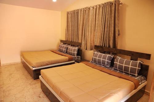 two beds sitting in a room with a window at Raaj Resort in Panvel