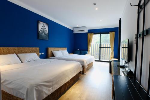 2 camas en una habitación con paredes azules en 琉球鳥巢旅店, en Shang-fu-ts'un