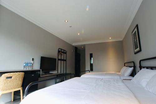 a bedroom with two beds and a desk and a television at 琉球鳥巢旅店 in Xiaoliuqiu