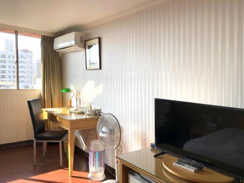 a hotel room with a desk and a tv in a room at Hermes Hotel in Hsinchu City