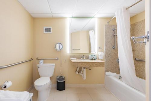 a bathroom with a toilet and a sink and a tub at Wyndham Omaha Hotel - West Dodge in Omaha