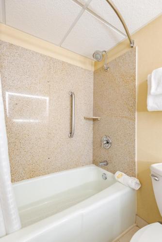 a bathroom with a white tub and a toilet at Wyndham Omaha Hotel - West Dodge in Omaha