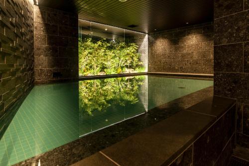 una piscina con riflesso di alberi in acqua di Hotel Global View Koriyama a Kōriyama