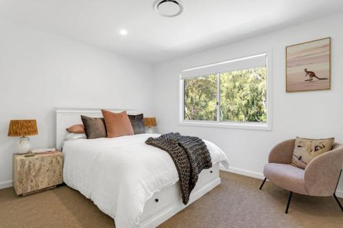a bedroom with a bed and a window and a chair at Manzi Jervis Bay in Huskisson