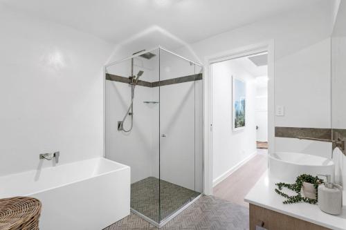 a white bathroom with a shower and a sink at Manzi Jervis Bay in Huskisson