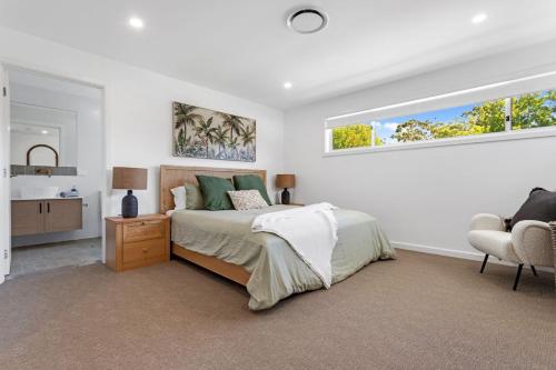 a bedroom with a bed and a chair and a window at Ilanga Jervis Bay-Heated Pool in Huskisson