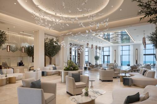 a lobby with white furniture and a large chandelier at Jumeirah Gulf of Bahrain Resort and Spa in Manama