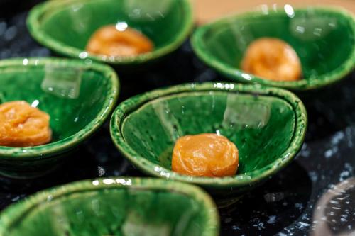 a group of green bowls with orange food in them at Mito Sannomaru Hotel in Mito