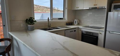 a kitchen with white marble counter tops and a sink at Stanley Village Waterfront Accommodation in Stanley