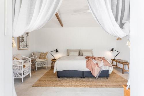 1 dormitorio con 1 cama con cortinas blancas en The Beach Hut en Vincentia