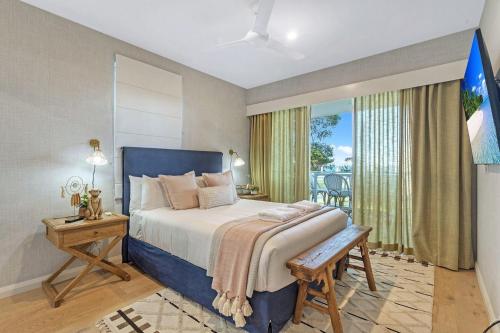 a bedroom with a bed and a table and a window at Bliss the Beach Jervis Bay in Huskisson